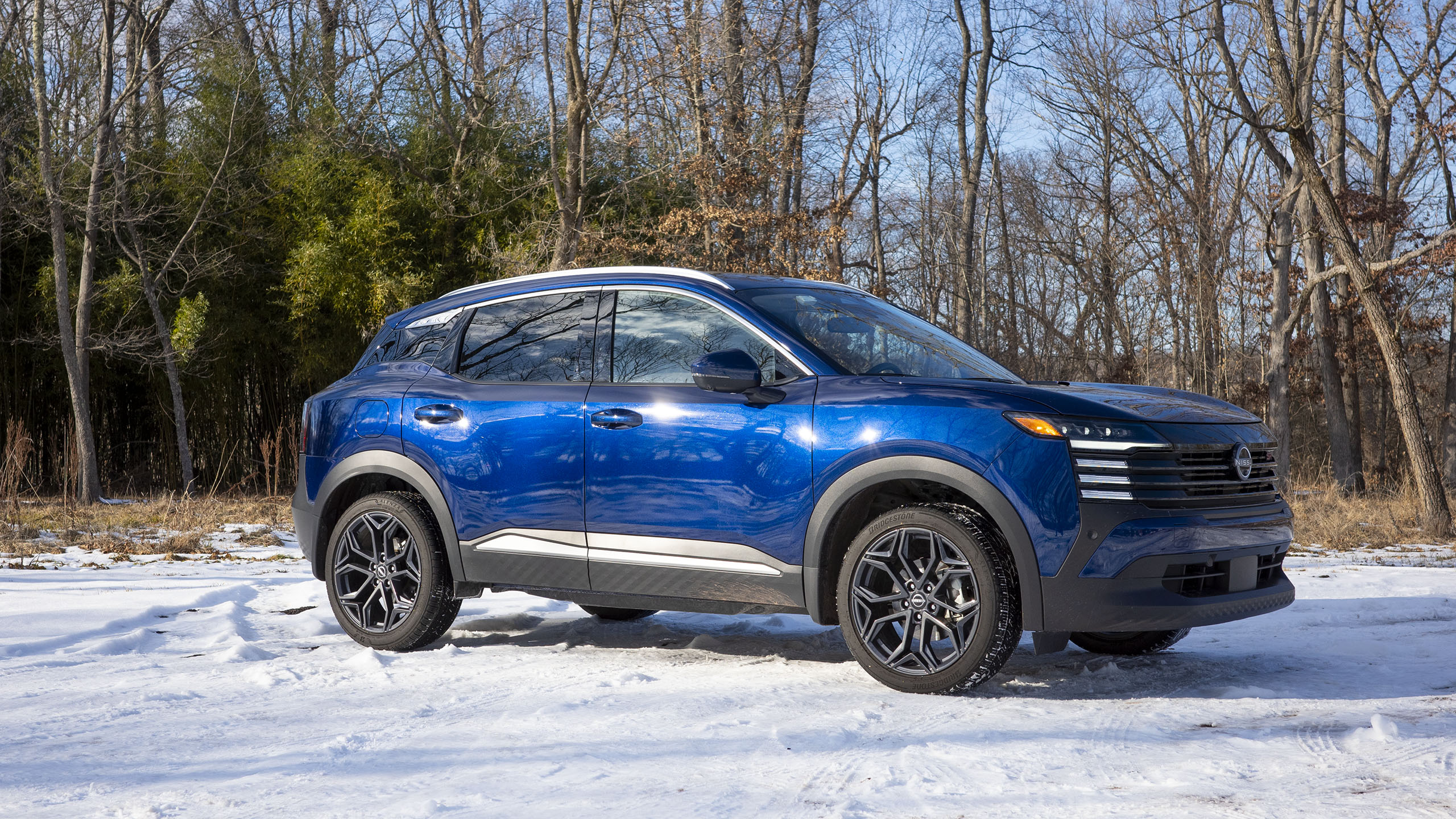 2025 Nissan chuta em azul, vista frontal de três quartos em um lote coberto de neve.