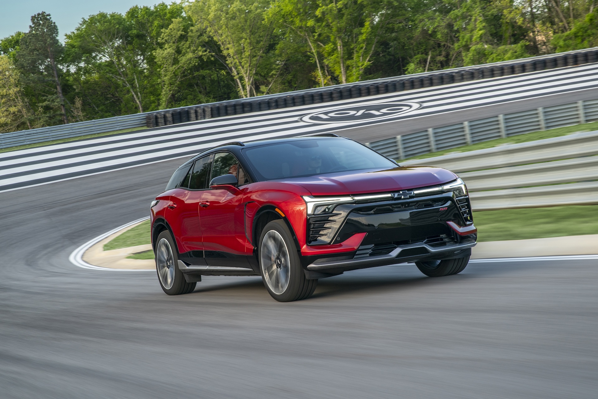 Frente 3/4 de um blazer EV SS em Radiant Red Driving em uma pista.